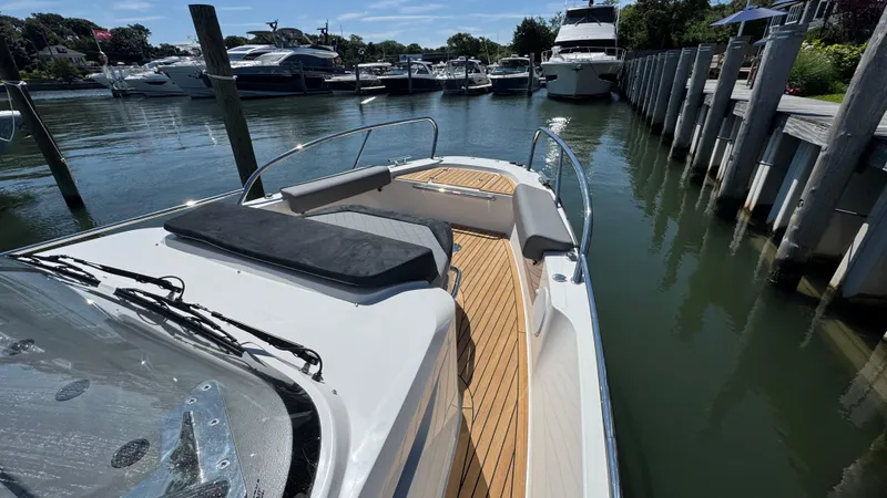 Slide: The Image of 2025 Nimbus T9 boat docked in a marina, featuring sleek design and wooden deck. - 38