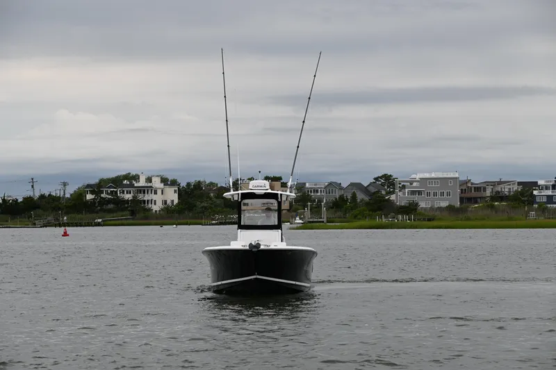 Slide: The Image of 2013 Sea Hunt Gamefish 27 boat on calm water, with coastal homes in the background. - 10
