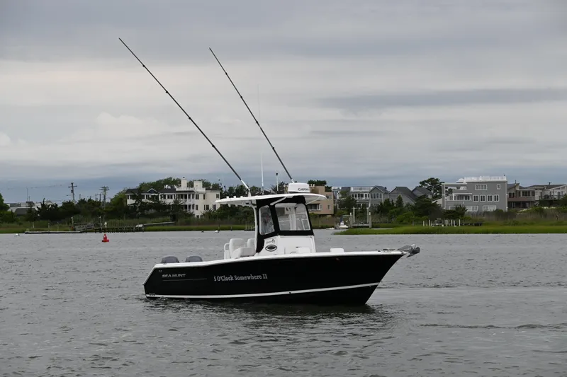 Slide: The Image of 2013 Sea Hunt Gamefish 27 boat on water, overcast sky, coastal houses in background. - 12