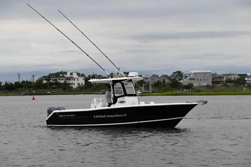 Slide: The Image of 2013 Sea Hunt Gamefish 27 boat on water, overcast sky, coastal homes in background. - 13