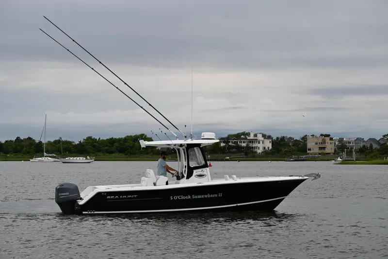 Slide: The Image of 2013 Sea Hunt Gamefish 27 boat on calm water, overcast sky, coastal background. - 14