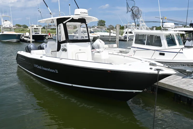 Slide: The Image of 2013 Sea Hunt Gamefish 27 boat docked in marina, featuring sleek black and white design. - 15