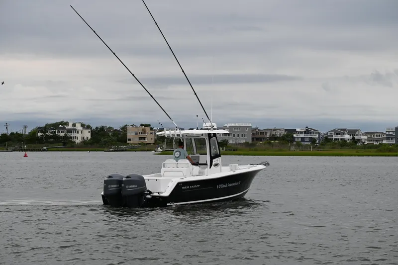 Slide: The Image of 2013 Sea Hunt Gamefish 27 boat on water, with dual Yamaha engines, near residential shoreline. - 2