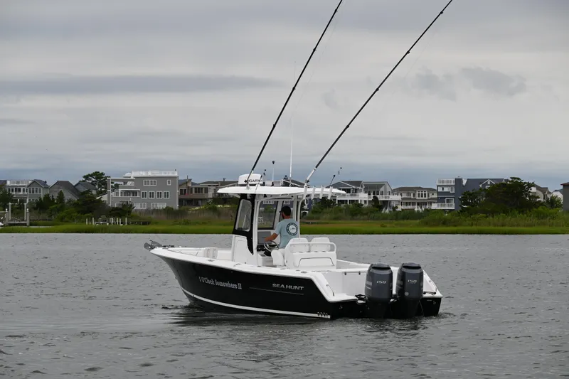 Slide: The Image of 2013 Sea Hunt Gamefish 27 boat on water, with coastal homes in the background. - 4
