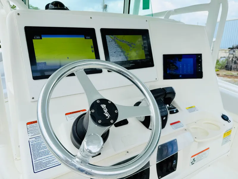 Slide: The Image of 2018 Mako 284 CC boat dashboard with steering wheel and navigation screens. - 12