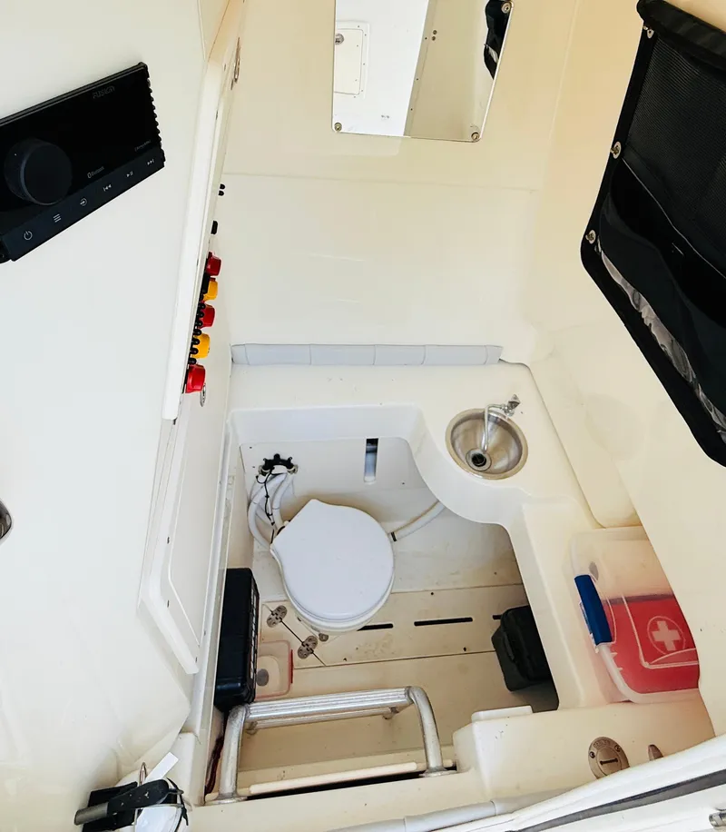 Slide: The Image of 2018 Mako 284 CC boat interior with toilet, sink, and storage compartments. - 13
