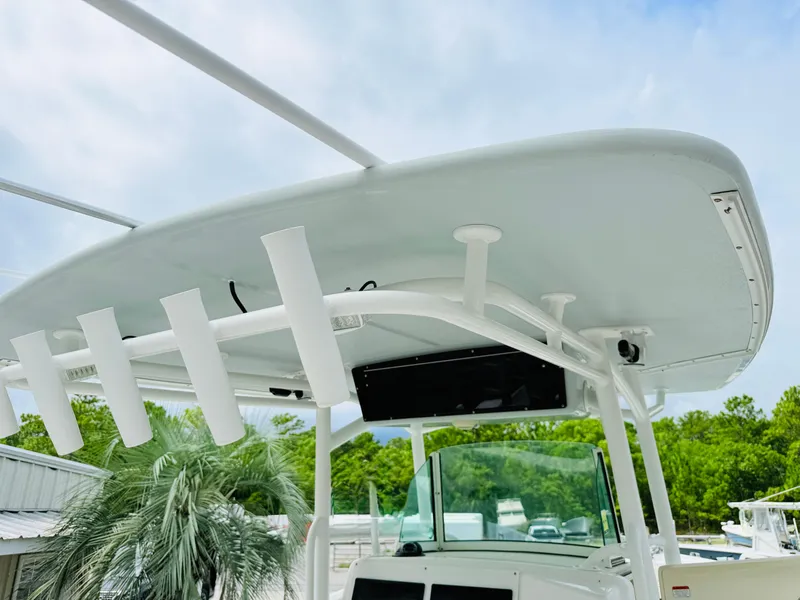 Slide: The Image of 2018 Mako 284 CC boat with T-top and rod holders, docked near palm trees. - 18