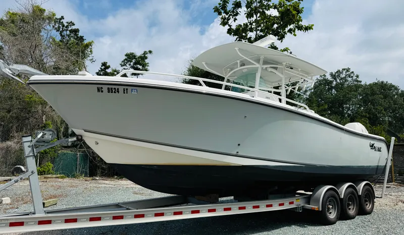 Slide: The Image of 2018 Mako 284 CC boat on trailer, side view, outdoors with trees in background. - 3