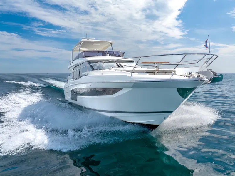 The Image of 2020 Prestige 590 Flybridge Cruiser navigating ocean waves under a clear blue sky. - 1