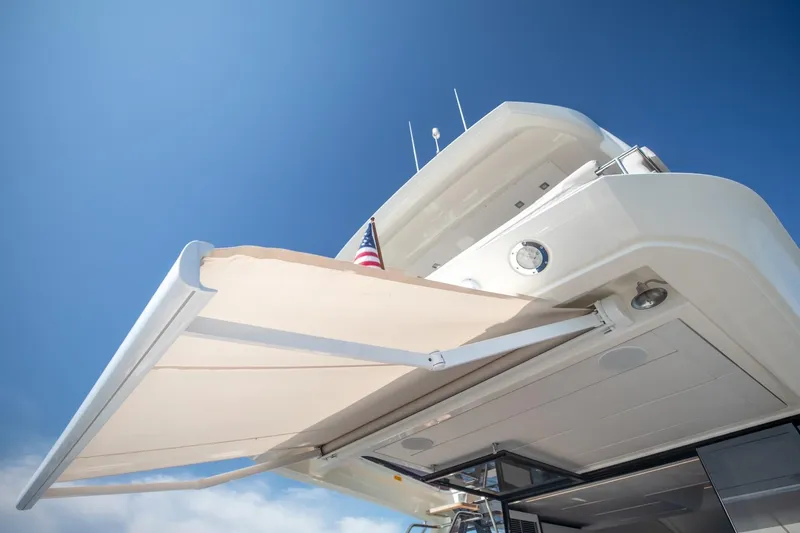 Slide: The Image of 2020 Prestige 590 Flybridge Cruiser with extended awning under clear blue sky. - 15