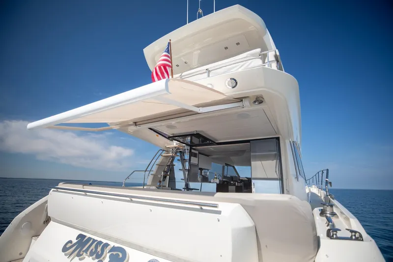 Slide: The Image of Prestige 590 Flybridge Cruiser 2020, rear view with American flag, on open water. - 16