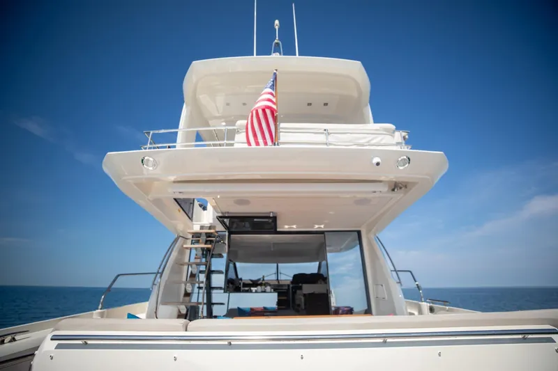 Slide: The Image of 2020 Prestige 590 Flybridge Cruiser on open sea, rear view with American flag. - 17