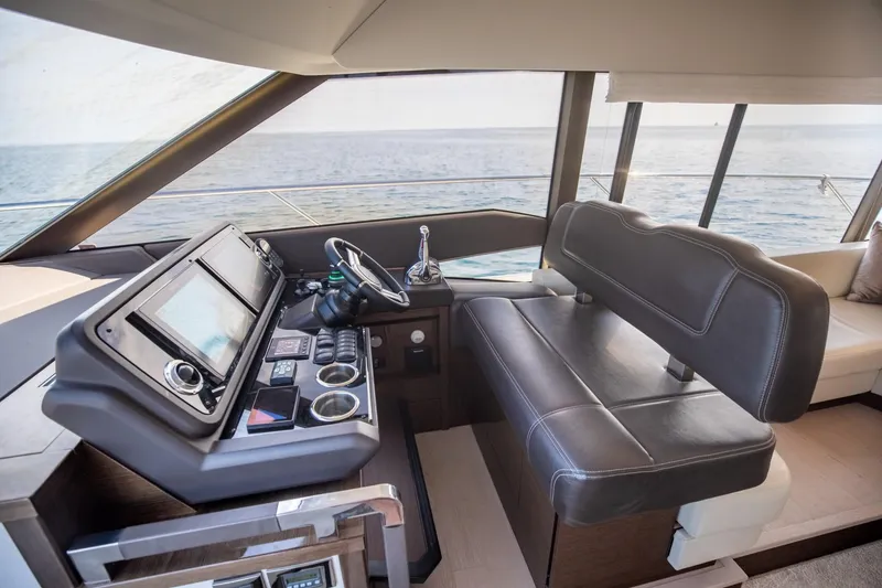Slide: The Image of 2020 Prestige 590 Flybridge Cruiser helm with leather seating and modern navigation controls. - 28