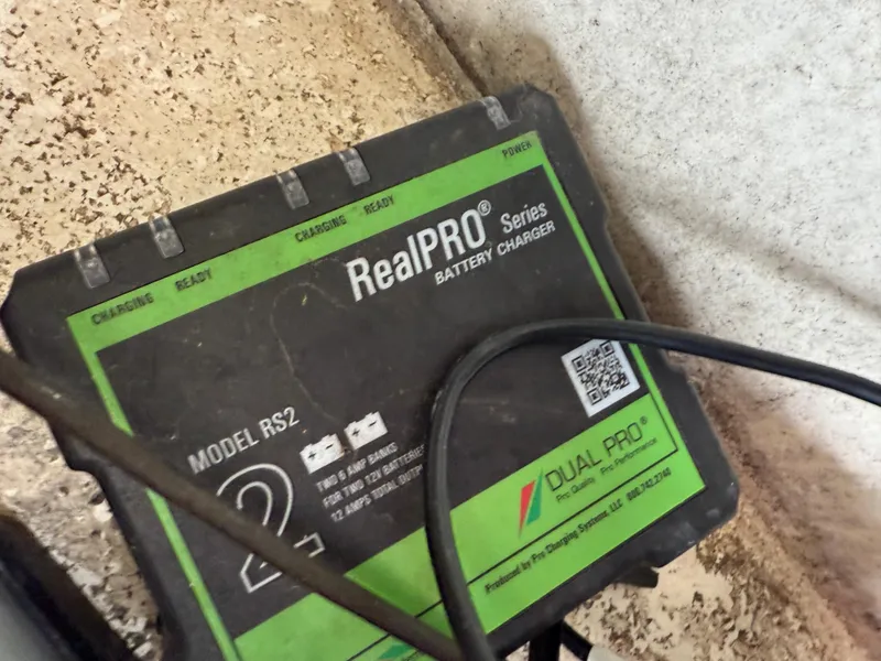 Slide: The Image of RealPRO Series battery charger, Model RS2, with cables on a textured surface. - 19