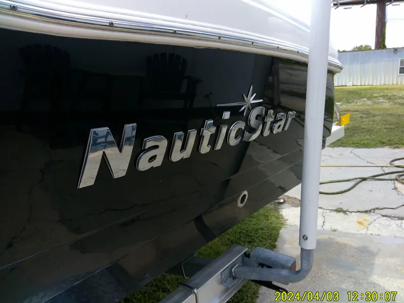 Slide: The Image of 2023 NauticStar 231 Hybrid boat, side view with logo, parked outdoors. - 16