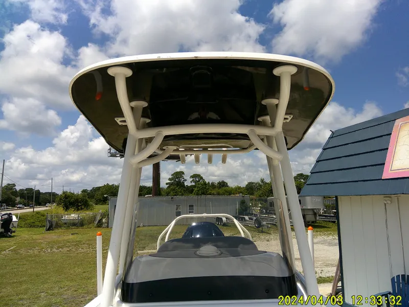 Slide: The Image of 2023 NauticStar 231 Hybrid boat with T-top, parked outdoors under a cloudy sky. - 26