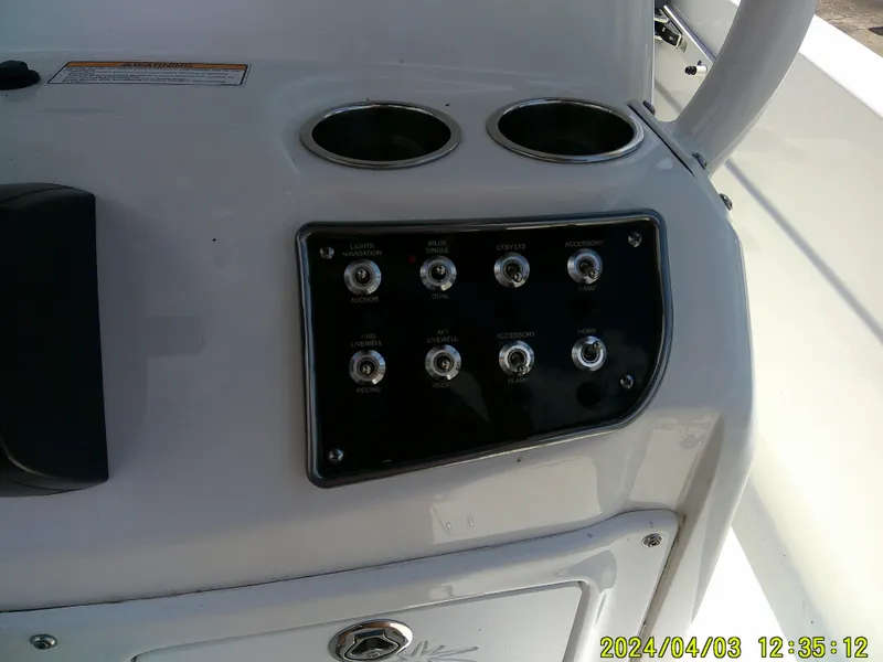 Slide: The Image of Control panel of 2023 NauticStar 231 Hybrid boat with switches and cup holders. - 39