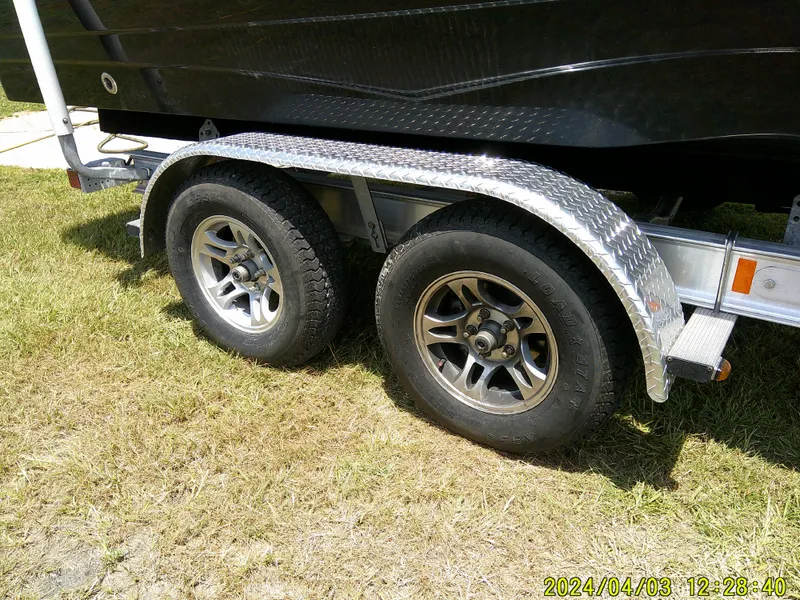 Slide: The Image of Trailer wheels of a 2023 NauticStar 231 Hybrid boat on grass. - 4