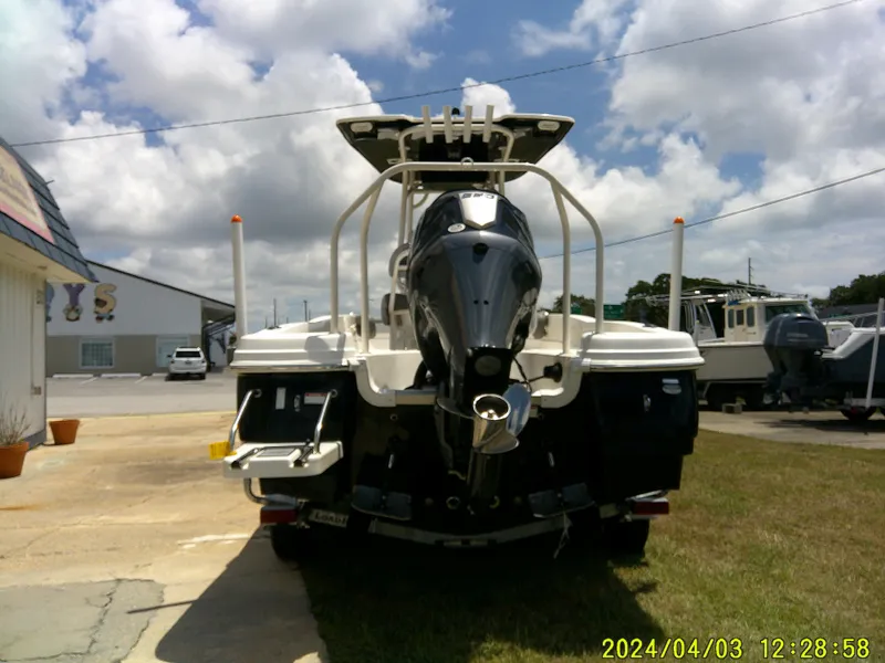 Slide: The Image of 2023 NauticStar 231 Hybrid boat with outboard motor, parked outdoors under cloudy sky. - 6