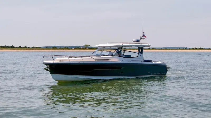Slide: The Image of 2024 Nimbus W11 boat cruising on calm waters near a sandy shoreline. - 1
