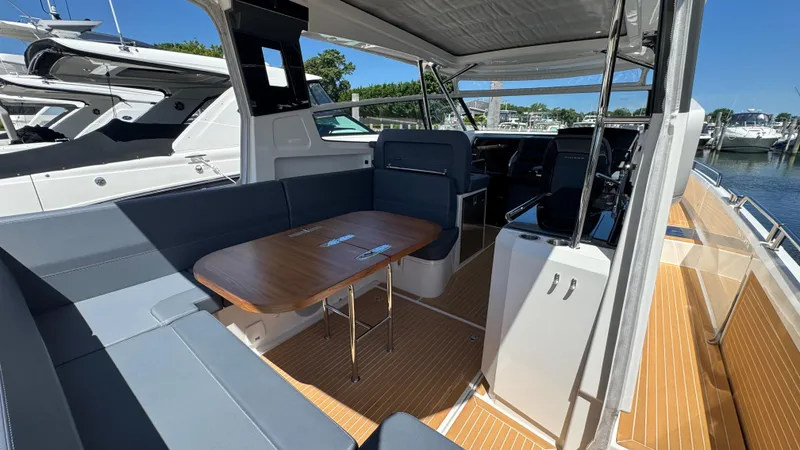 Slide: The Image of 2024 Nimbus W11 boat interior with seating, table, and helm, docked at marina. - 17