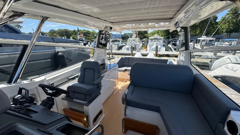 Slide: The Image of 2024 Nimbus W11 boat interior with modern seating and helm, docked at a marina. - 26