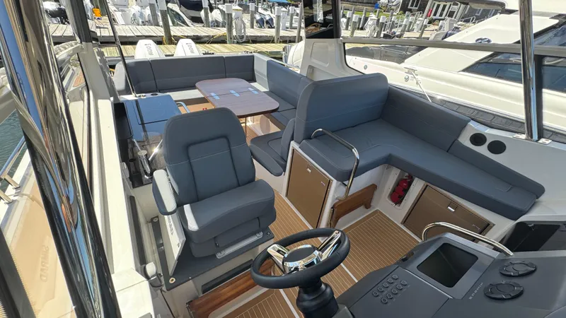 Slide: The Image of 2024 Nimbus W11 boat interior with modern seating and steering wheel at a marina. - 27