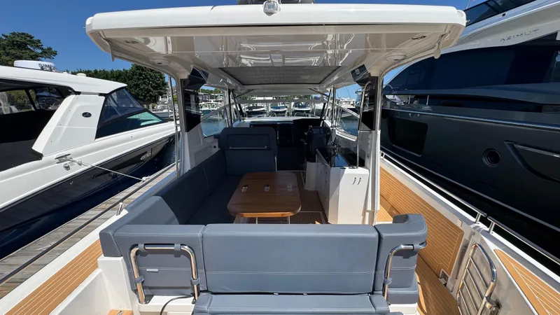 Slide: The Image of 2024 Nimbus W11 boat interior with seating and table, docked alongside other yachts. - 15