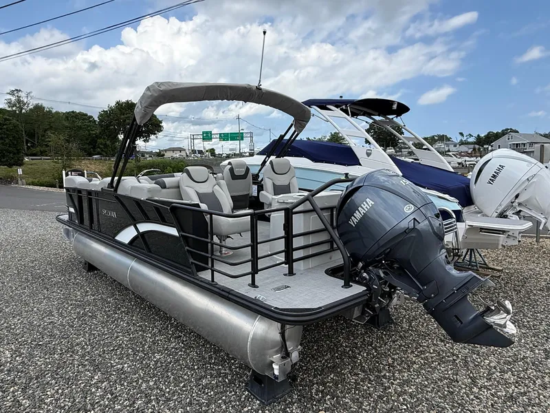 Slide: The Image of 2025 Sylvan L3 Party Fish pontoon boat with Yamaha outboard motor, parked on gravel. - 5