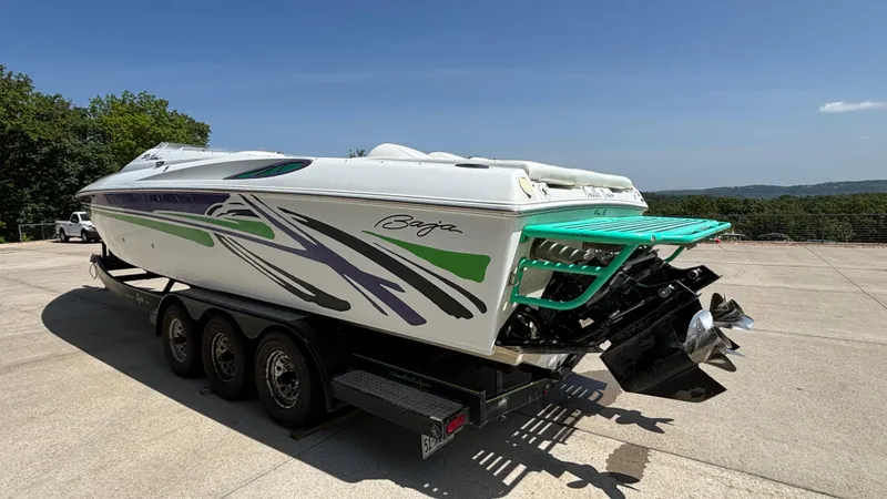 Slide: The Image of 2005 Baja 33 Outlaw boat on trailer, vibrant graphics, sunny day, outdoor setting. - 5