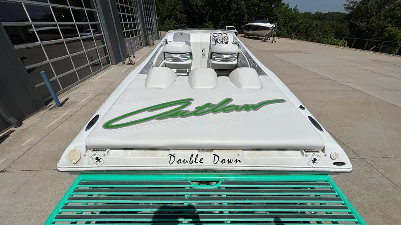 Slide: The Image of 2005 Baja 33 Outlaw speedboat, white with green accents, parked outdoors. - 8