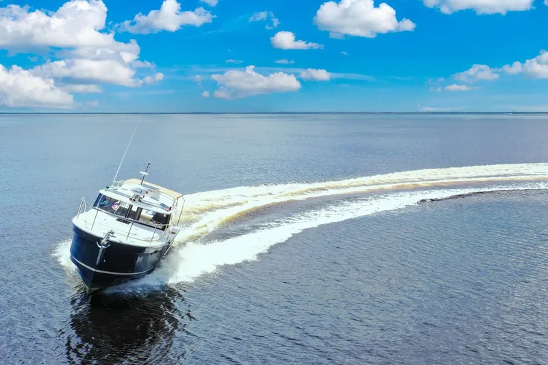 Slide: The Image of 2024 Ranger Tugs R-27 cruising on open water under a clear blue sky. - 1