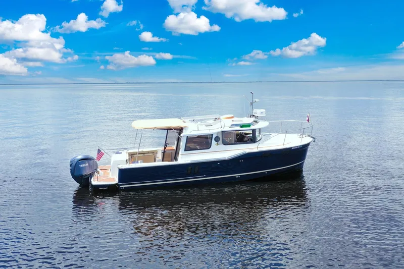 Slide: The Image of 2024 Ranger Tugs R-27 boat on calm water under a clear blue sky. - 10