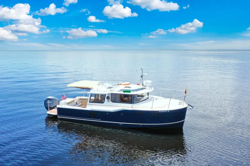 Slide: The Image of 2024 Ranger Tugs R-27 boat cruising on calm blue waters under a clear sky. - 11