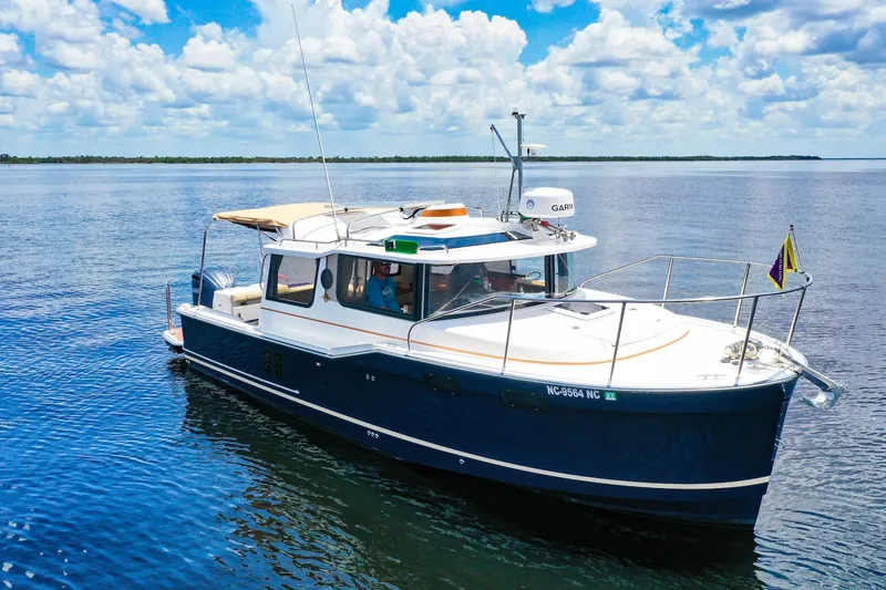 Slide: The Image of 2024 Ranger Tugs R-27 boat cruising on calm water under a partly cloudy sky. - 12