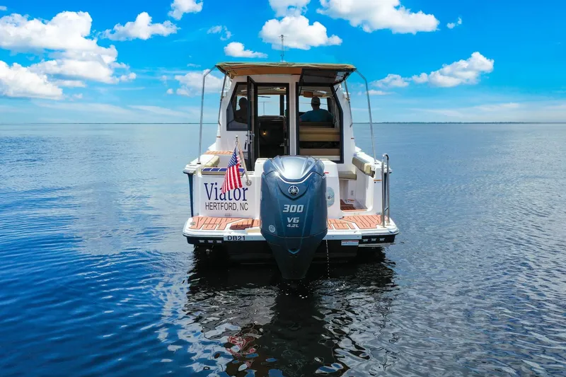 Slide: The Image of 2024 Ranger Tugs R-27 boat on calm water, rear view with outboard motor. - 13