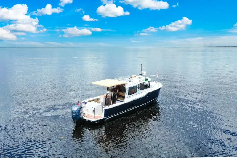 Slide: The Image of 2024 Ranger Tugs R-27 boat on calm water under a clear blue sky. - 14