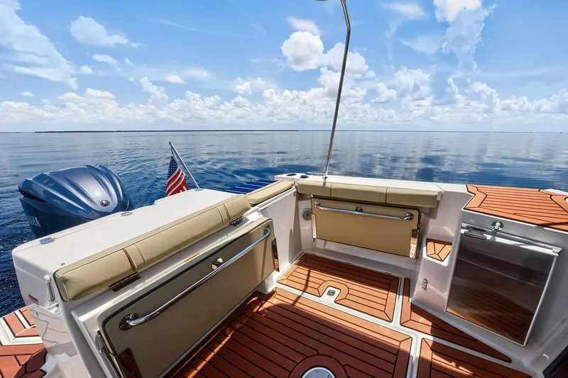 Slide: The Image of 2024 Ranger Tugs R-27 boat deck with seating, American flag, and serene ocean view. - 15