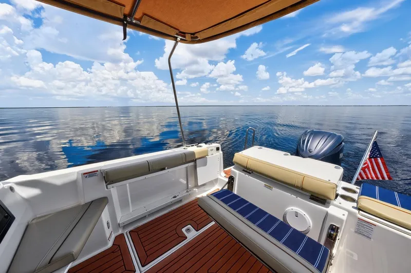 Slide: The Image of 2024 Ranger Tugs R-27 boat interior with ocean view, featuring seating and American flag. - 17