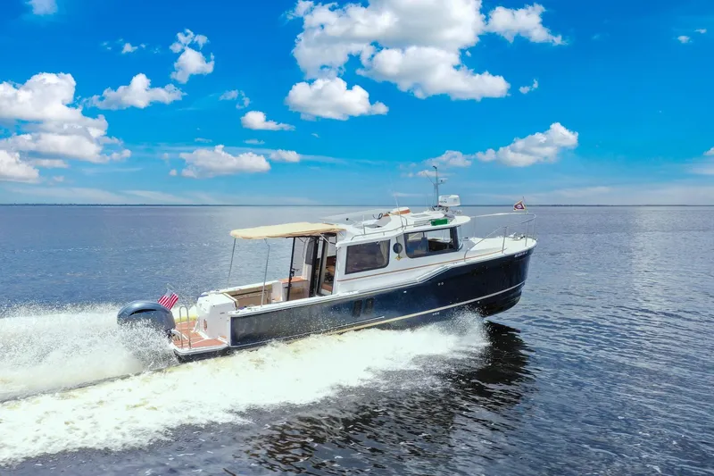 Slide: The Image of 2024 Ranger Tugs R-27 cruising on open water under a clear blue sky. - 2