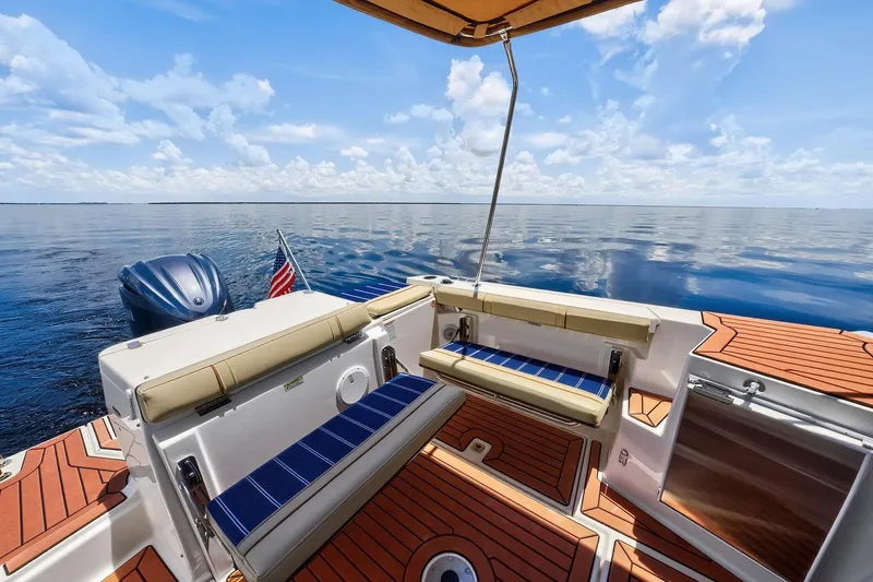Slide: The Image of 2024 Ranger Tugs R-27 boat deck with seating, ocean view, and American flag. - 21