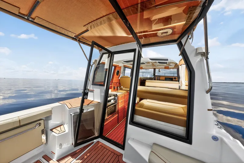 Slide: The Image of 2024 Ranger Tugs R-27 interior with luxurious seating and modern amenities on calm waters. - 25