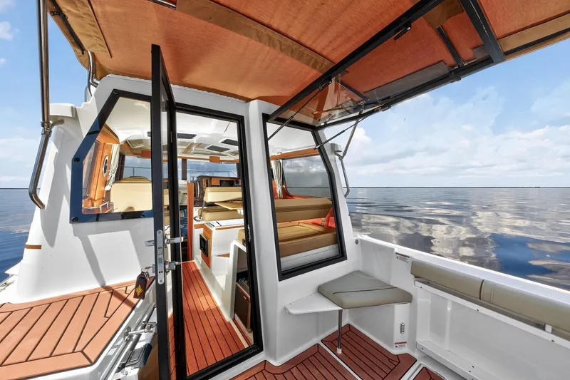 Slide: The Image of 2024 Ranger Tugs R-27 interior with open cabin, wood accents, and ocean view. - 26