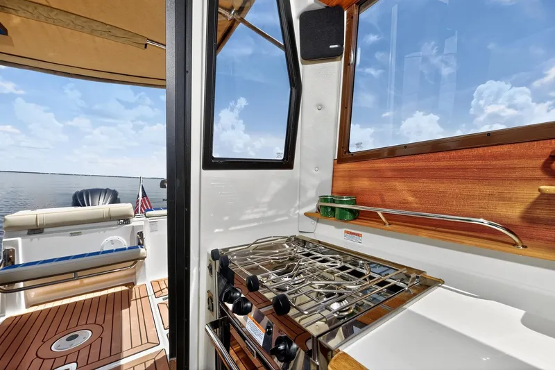 Slide: The Image of 2024 Ranger Tugs R-27 interior with stove, wooden accents, and ocean view. - 27