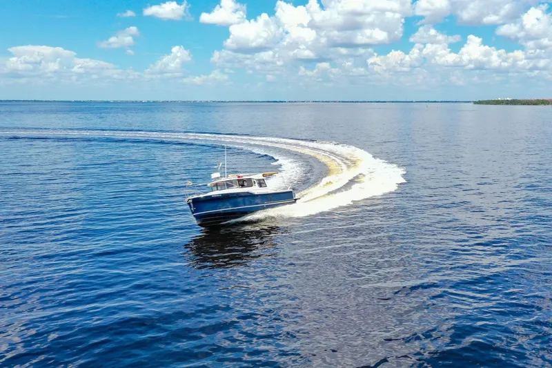 Slide: The Image of 2024 Ranger Tugs R-27 cruising on open water under a bright blue sky. - 3