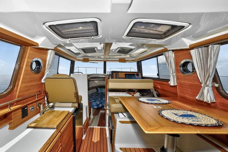 Slide: The Image of 2024 Ranger Tugs R-27 interior with wood accents, dining area, and helm station. - 30