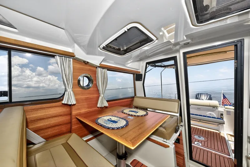 Slide: The Image of Interior of 2024 Ranger Tugs R-27 boat with wooden dining area and ocean view. - 32