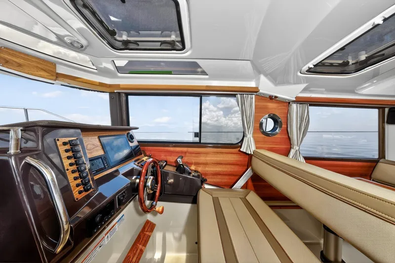 Slide: The Image of 2024 Ranger Tugs R-27 interior with modern helm, wood accents, and panoramic windows. - 33