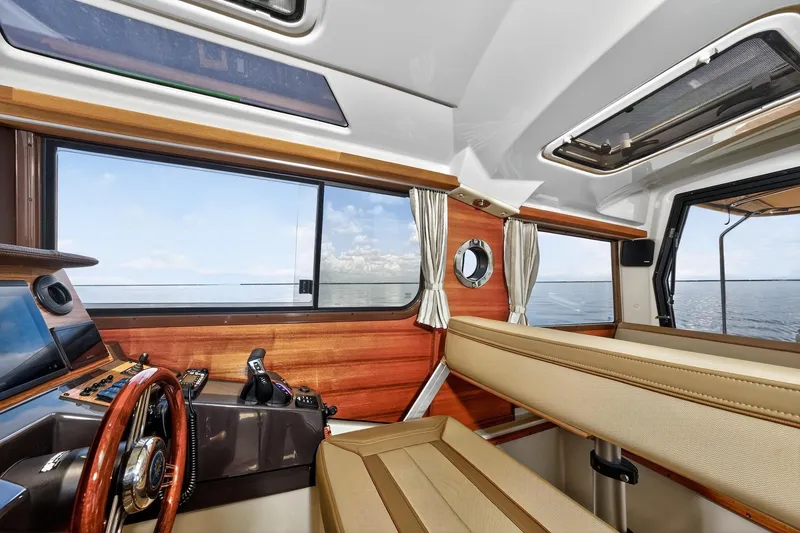 Slide: The Image of 2024 Ranger Tugs R-27 interior with wood accents and ocean view. - 34