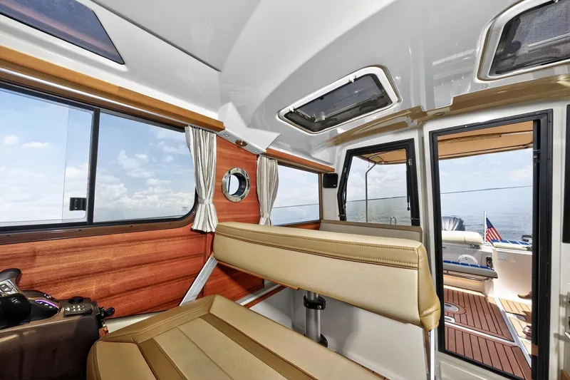 Slide: The Image of 2024 Ranger Tugs R-27 interior with wood accents, large windows, and comfortable seating. - 35